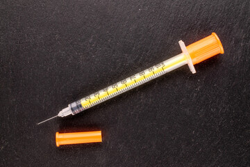 One medical syringe on slate stone, macro, top view.