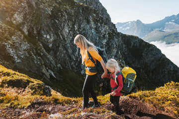 Mother and daughter hiking in mountains, family adventure healthy lifestyle hobby outdoor, parent and kid climbing together active vacations with backpack - 707207897