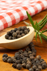 poivre en grains, en gros plan, dans une cuillère en bois