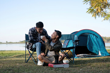 Asian LGBTQ couple drinking coffee in a romantic camping tent. LGBTQ couple drinking coffee in a camping tent, enjoying nature, forest, camping atmosphere, LGBTQ, gay, gay men.