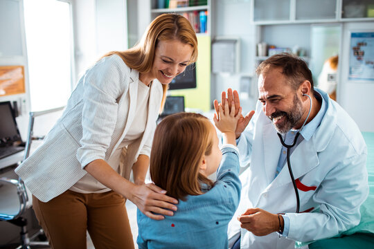 Little girl high fiving doctor during hospital visit with mother