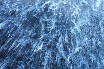The pattern of the frozen and cracked surface of the lake. Natural ice texture