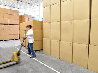 woman works with forklift truck in a warehouse with cartons