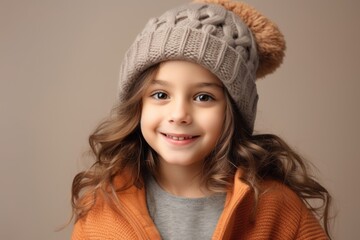 A closeup portrait of a cute little girl in a warm hat and sweater.