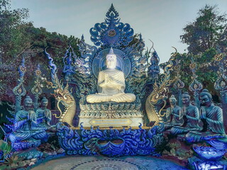 Praying monks and Buddha statues at Wat Rong Suea Ten Blue temple, Chiang Rai, Thailand - obrazy, fototapety, plakaty
