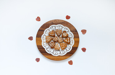 Top view of homemade heart-shaped cookies decorated with sugar icing on wooden tray on white table. Homemade baking recipe. Congrats on Valentine's Day, birthday or March 8th. Close-up, flat lay