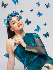 A beautiful woman in a blue dress is surrounded by blue butterflies, a brunette in a tiara of butterflies on a white background
