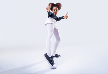 African american little girl in showing thumb up, leg, happy child afro girl showing sneakers, shoes. Happy young black girl in stylish outfit showing thumb ups and shoe. Human gestures concept