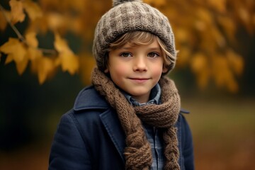 Portrait of a cute little boy in a hat and scarf in autumn park