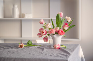 pink spring flowers in white ceramic vase in modern home interior