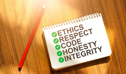 ETHICS RESPECT CODE HONESTY INTEGRITY on notebook with red pencil on wooden background