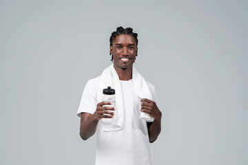 Smiling athletic black man wearing white t-shirt holding water bottle