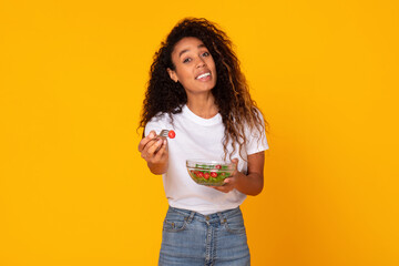 black woman with vegetable salad offering fork to you, studio