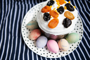 Easter eggs and Easter cake are on a plate, lying on a striped blue apron. Easter religious holiday concept.