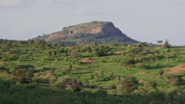 Extreme wide shot of a rocky hill across the savannah in the afternoon