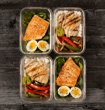 Meal prep meals with salmon, spinach and a hard boiled egg, chicken, rices and roasted veggies 