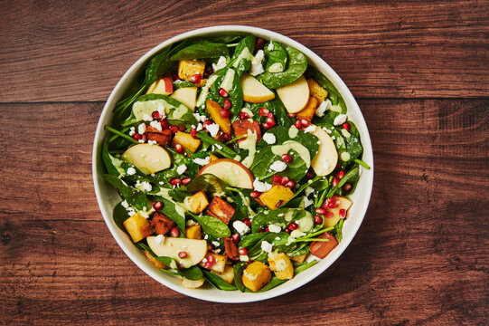 Autumn salad with apples, squash, pomegranate, cheese and spinach