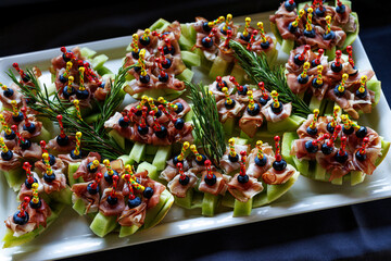 A platter of appetizing hors d oeuvres with colorful skewers on a black background.