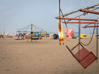 Carousel with wooden horses in beach for kids fun. Merry go round as part of fun activities in...