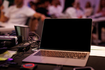 A presenter using a laptop in a conference room with a large audience - obrazy, fototapety, plakaty