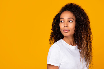 African American young woman looking away thoughtfully against yellow backdrop