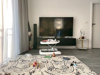 A large room with a children's rug, toys and walkers