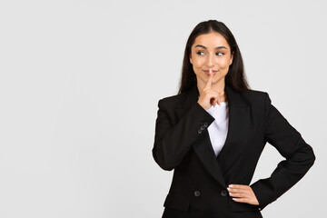 Businesswoman with finger on lips signaling silence
