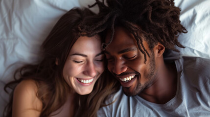 Happy couple, bed and laughing in relax for morning, bonding or intimate relationship at home. Interracial man and woman smiling with laugh in joyful happiness or relaxing weekend together - obrazy, fototapety, plakaty