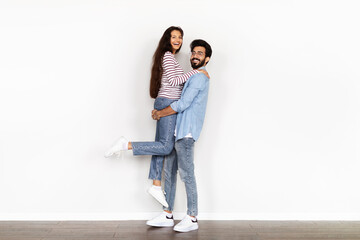 Happy indian couple have fun over white wall background
