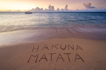 Handwritten Hakuna Matata ( no trouble) on sandy beach at sunset,relax and summer concept, Zanzibar...