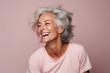 Happy senior woman with grey hair and t-shirt on pink background