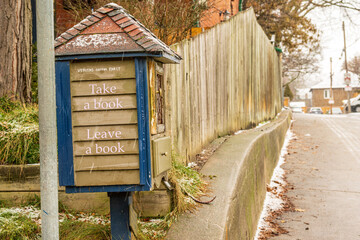 Take a book. Leave a book: free book exchange box (hand made) on a residential street shot on a wet...