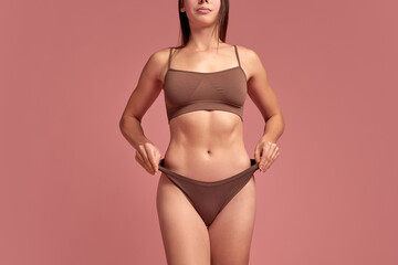 Fototapeta premium Successful story of weight loss. Cropped image of slim female body, model standing in underwear and showing her body changes after loosing weight. Concept of beauty, health and body care, sport, diet