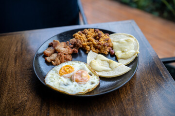 wide shot of breakfast plate with many items including eggs pork rinds corn cake with cheese and rice at breakfast spot