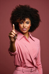 Fototapeta na wymiar Beautiful african american woman with afro hairstyle in pink suit pointing finger at camera