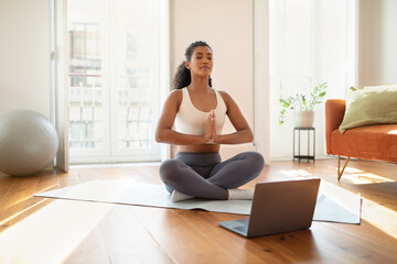 Fototapeta na wymiar Sporty young woman engaging in online yoga class at home