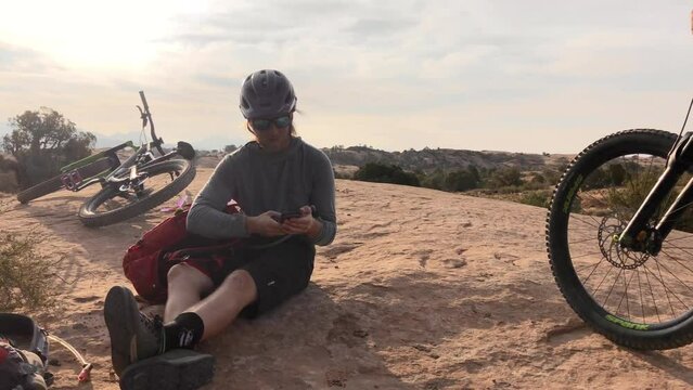 Nature, phone and man relax after mountain bike travel on outdoor ride, desert journey or off road exercise. Bicycle, smartphone and athlete doing internet search for online info on cycling trip