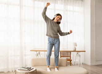 Cheerful young Caucasian lady in wireless headphones listening to music