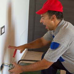 Image of an electrician as he installs an electrical plug and gets an electric shock. Job security
