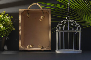 Arrière plan noir avec une cage à oiseau vide et une caisse en bois vide..	