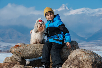 Boy with shih tzu dog winter portrait on mountains background