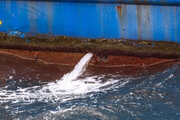 a water hose spewing out of the side of a ship