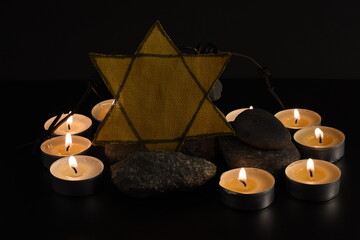 Naklejka premium Stones, David star, candles, barbed wire, Israel flag on dark background. Holocaust concept.