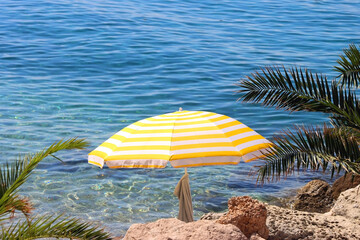 Colorful parasol on the beaach, by the sea. Sunny summer day. Selective focus.