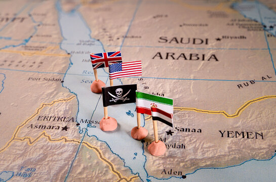 Flags of the United States and Iran and their respective allies surrounding a pirate insignia onto a map of the Red Sea region. It symbolically represents the intricate geopolitical dynamics and