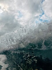 waves crash over a body of water under a cloudy sky