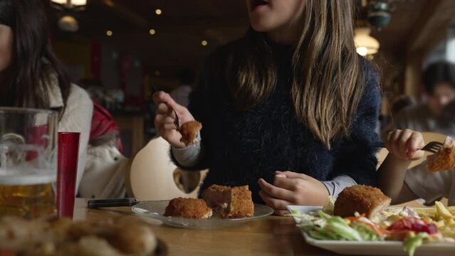 Cozy Dining Delight - Little Girl Enjoying Cordon Bleu Chicken At Family Mealtime In Wooden Interior Diner, People Eating Food At Restaurant