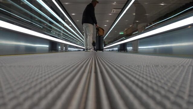 Stockholm, Sweden A male traveler on a rolling sidewalk at Arlanda Airport with bags. 