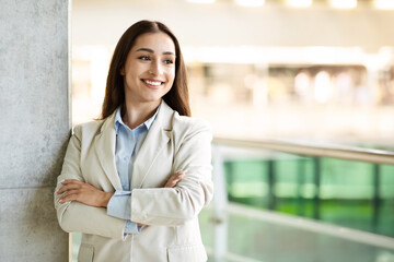 A professional young woman with long hair, dressed in a light beige blazer