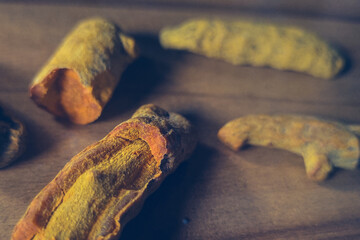 A bunch of turmeric root condimemt broken inside with orange color scattered on wooden floor with shadows